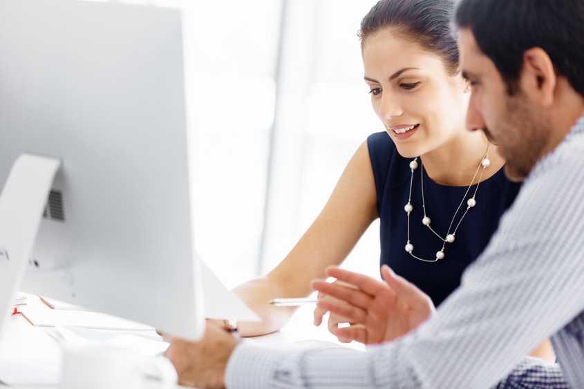 A Cappers representative discussing web applications with a business owner in front of a desktop computer.